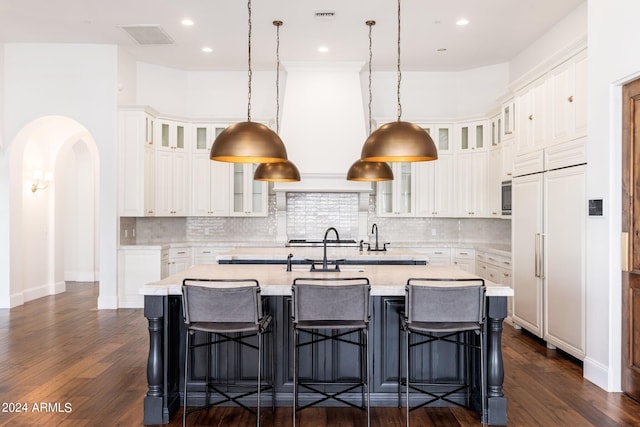 kitchen featuring a breakfast bar, a kitchen island with sink, dark hardwood / wood-style floors, and white cabinetry