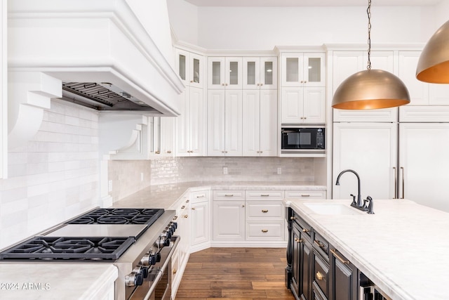 kitchen with hanging light fixtures, black microwave, sink, custom exhaust hood, and white cabinetry