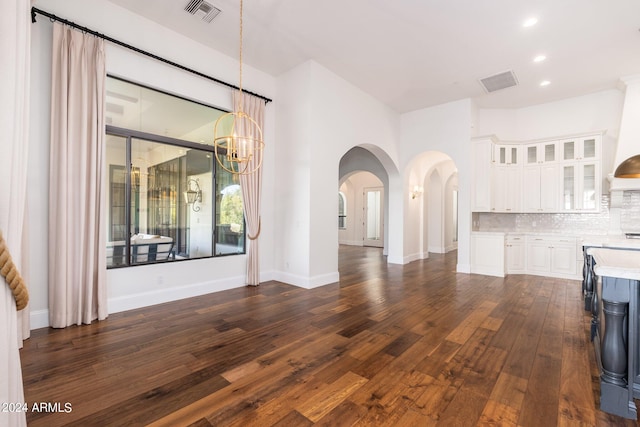 unfurnished living room with a notable chandelier and dark hardwood / wood-style floors