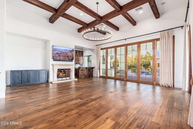 unfurnished living room featuring a towering ceiling, beamed ceiling, dark hardwood / wood-style flooring, and a chandelier