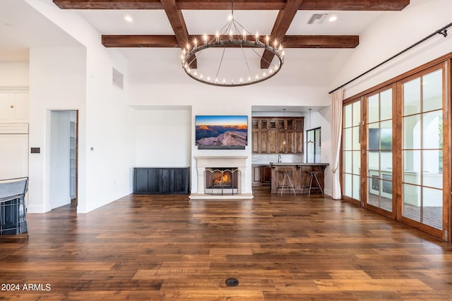 unfurnished living room with beamed ceiling, a notable chandelier, and dark hardwood / wood-style floors