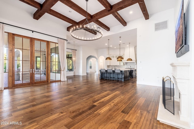 unfurnished living room with coffered ceiling, french doors, beamed ceiling, a chandelier, and dark hardwood / wood-style flooring