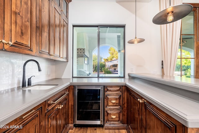 bar with sink, light wood-type flooring, backsplash, hanging light fixtures, and wine cooler