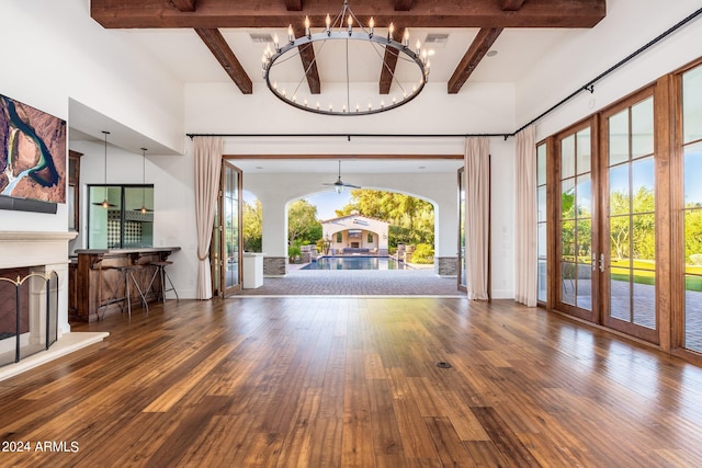 unfurnished living room featuring a wealth of natural light, beam ceiling, and dark hardwood / wood-style floors