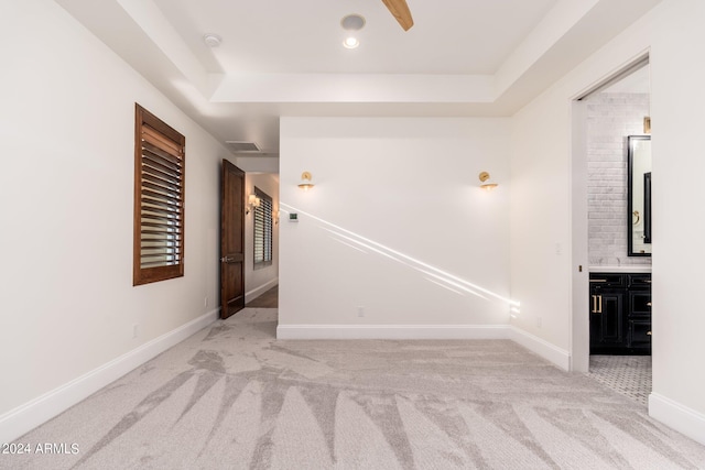 carpeted spare room with a raised ceiling