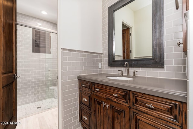 bathroom with a shower with door, vanity, and tile walls