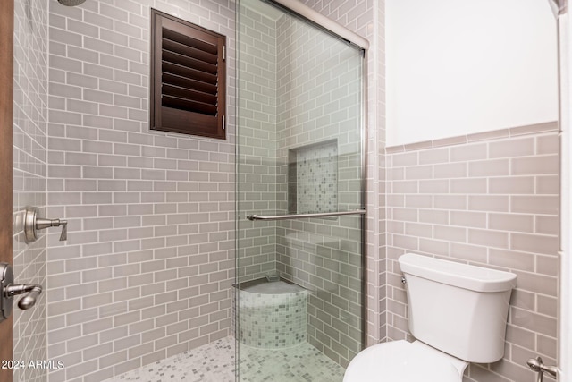 bathroom featuring toilet and a shower with shower door