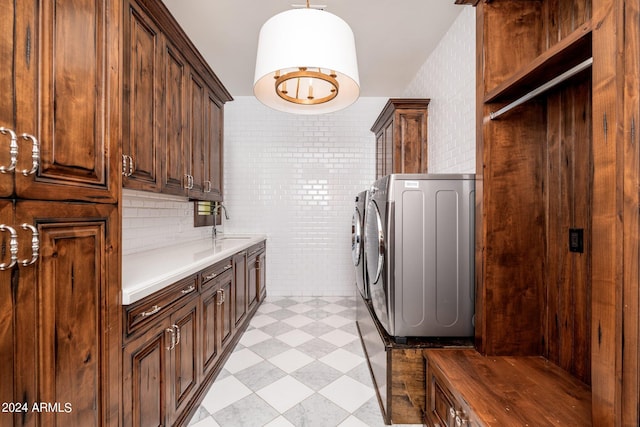 clothes washing area with cabinets, tile walls, sink, and washing machine and clothes dryer