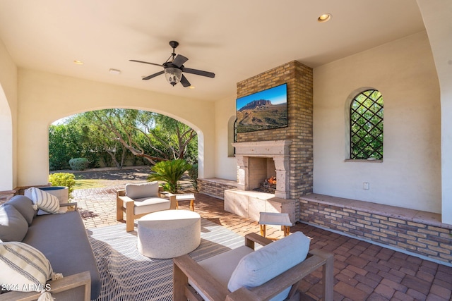 view of patio featuring ceiling fan and an outdoor living space with a fireplace