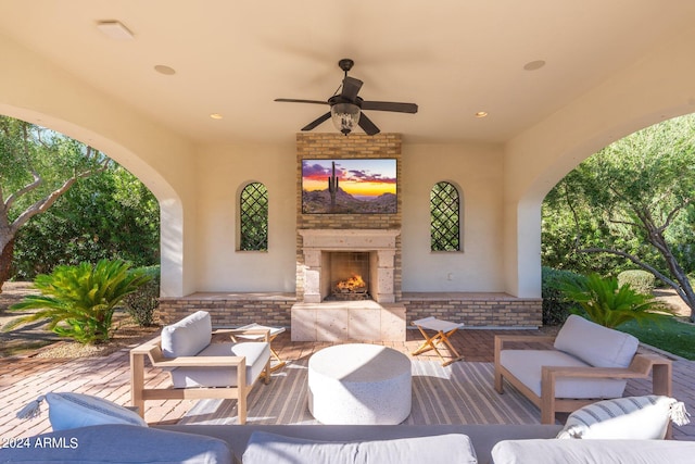 view of patio / terrace with ceiling fan and an outdoor living space with a fireplace