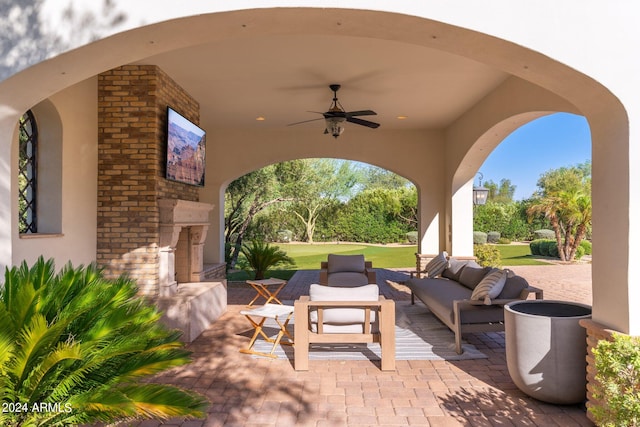 view of patio with ceiling fan and an outdoor living space with a fireplace