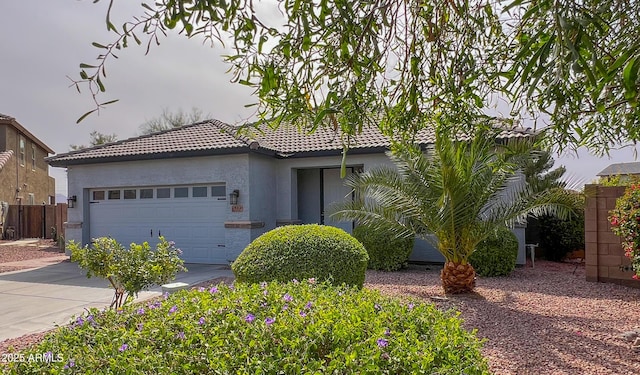 view of front facade featuring fence, driveway, stucco siding, a garage, and a tiled roof