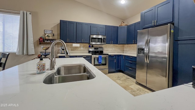 kitchen featuring blue cabinets, a sink, stainless steel appliances, decorative backsplash, and vaulted ceiling