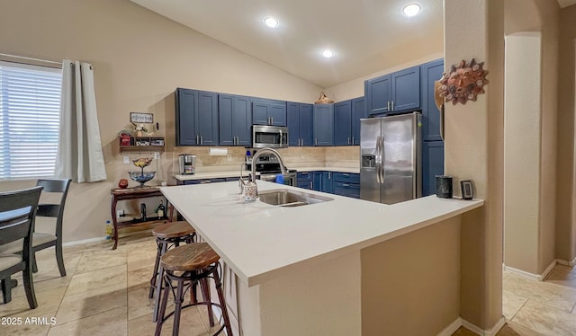 kitchen with blue cabinets, a kitchen breakfast bar, tasteful backsplash, appliances with stainless steel finishes, and vaulted ceiling