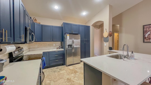 kitchen featuring blue cabinetry, stainless steel appliances, arched walkways, and light countertops