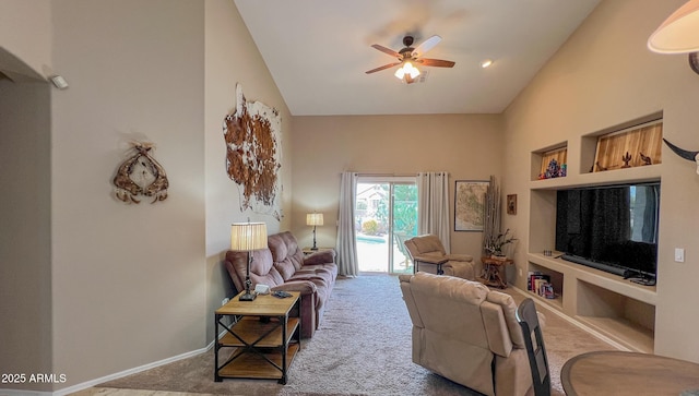 carpeted living area with high vaulted ceiling, built in shelves, baseboards, and ceiling fan