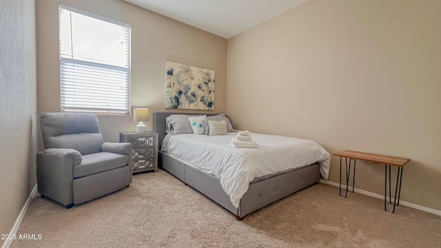 bedroom featuring lofted ceiling, light colored carpet, and baseboards