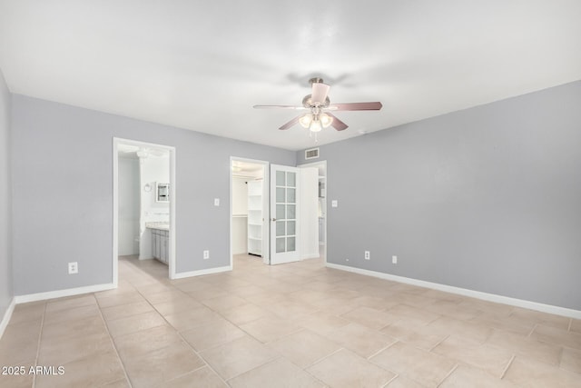 unfurnished bedroom featuring a walk in closet, ensuite bath, ceiling fan, light tile patterned floors, and a closet