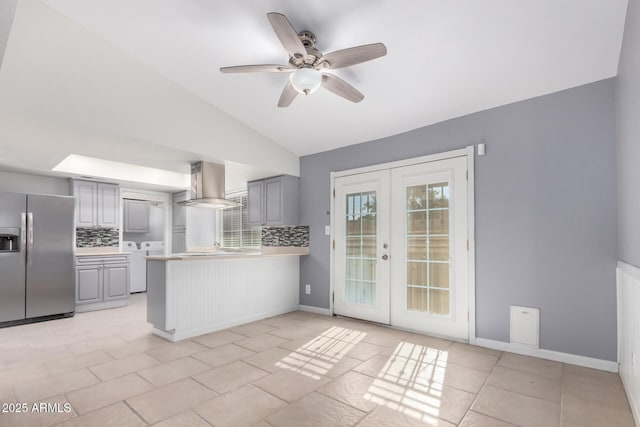 kitchen with wall chimney exhaust hood, tasteful backsplash, stainless steel fridge with ice dispenser, vaulted ceiling, and gray cabinets