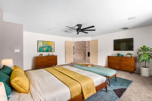 bedroom with a fireplace, ceiling fan, and light colored carpet