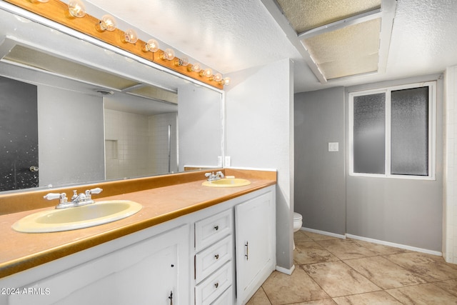 bathroom featuring tiled shower, vanity, a textured ceiling, tile patterned flooring, and toilet