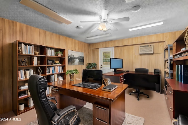 carpeted home office with a textured ceiling, wood walls, a wall mounted AC, and ceiling fan