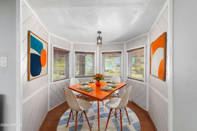 dining area with hardwood / wood-style flooring, wooden walls, and a wealth of natural light