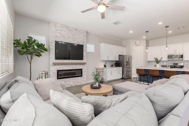 3081 E Desert Broom Pl, Chandler, AZ 85286 - living room with ceiling fan, light wood-style flooring, a stone fireplace, recessed lighting, and healthy amount of natural light