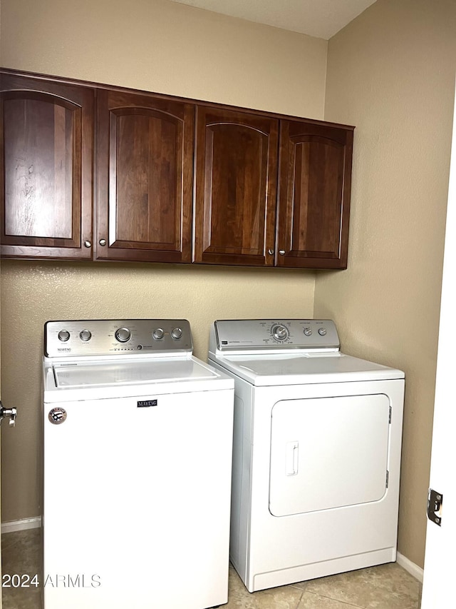 washroom with light tile patterned floors, separate washer and dryer, and cabinets