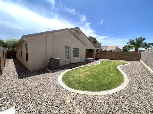 back of house with cooling unit and a lawn