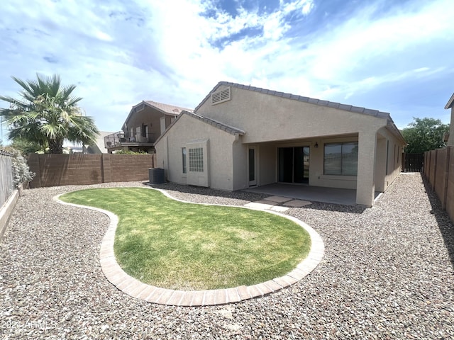 back of property with central AC unit, a lawn, and a patio