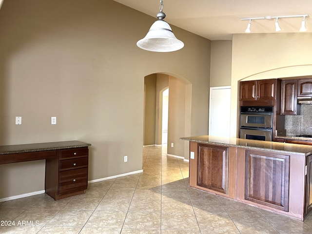 kitchen featuring decorative backsplash, dark brown cabinetry, hanging light fixtures, light tile patterned floors, and double oven