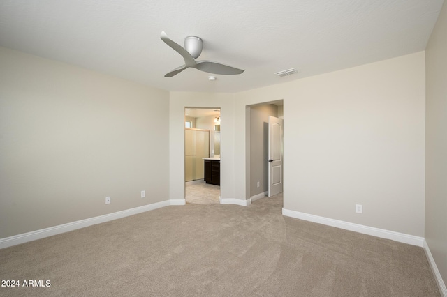 unfurnished bedroom with baseboards, visible vents, light colored carpet, and ensuite bath