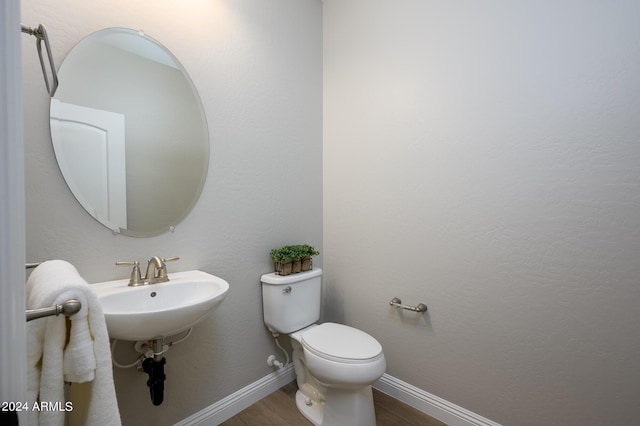 bathroom with toilet, a sink, baseboards, and wood finished floors