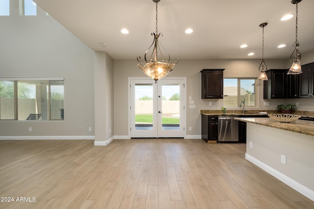 kitchen with french doors, light stone counters, light hardwood / wood-style floors, stainless steel dishwasher, and pendant lighting