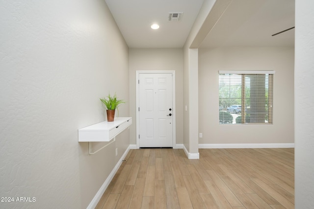 foyer with baseboards, light wood finished floors, and visible vents