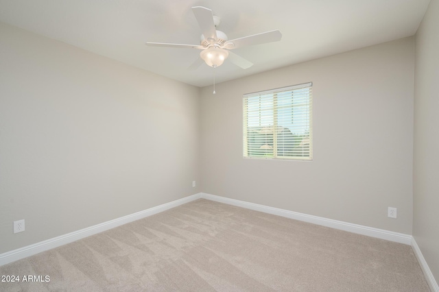 empty room with baseboards, a ceiling fan, and light carpet
