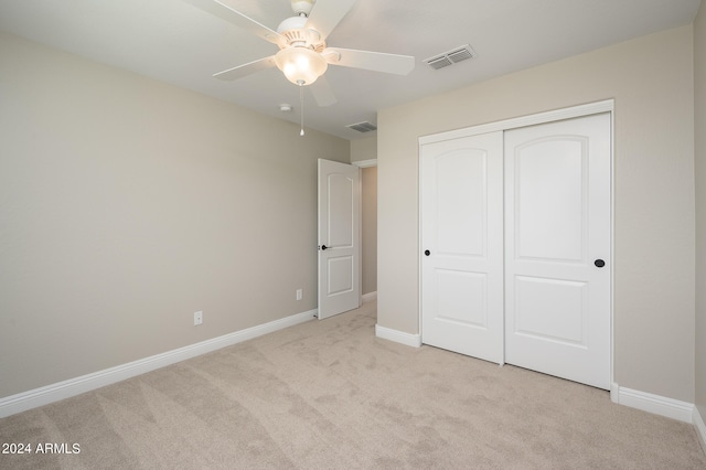 unfurnished bedroom with ceiling fan, light colored carpet, and a closet