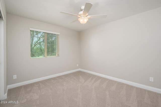 carpeted empty room featuring baseboards and a ceiling fan