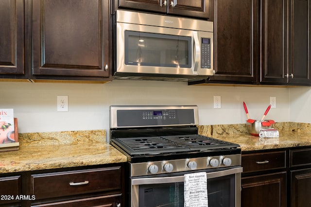 kitchen featuring dark brown cabinetry, stainless steel appliances, and light stone countertops