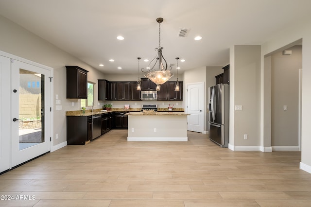 kitchen featuring stainless steel appliances, light hardwood / wood-style floors, decorative light fixtures, and a center island