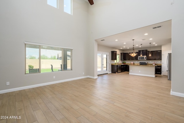 unfurnished living room with light hardwood / wood-style flooring and a high ceiling