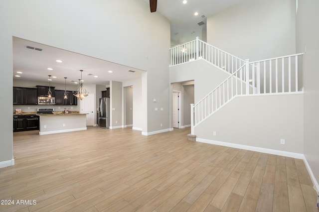 unfurnished living room with stairway, light wood-type flooring, baseboards, visible vents, and recessed lighting