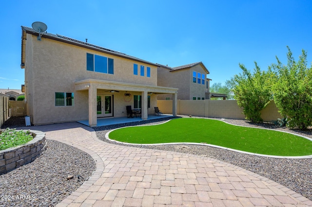 rear view of property with stucco siding, french doors, a fenced backyard, ceiling fan, and a patio area