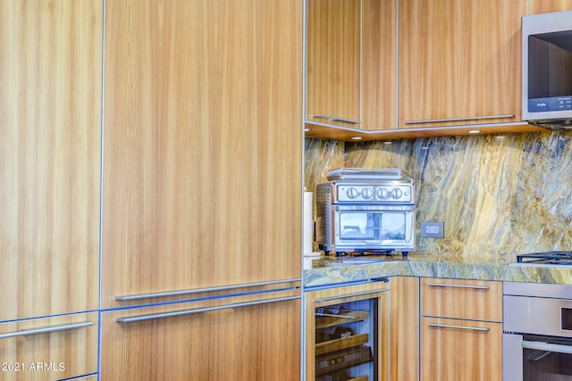 kitchen with backsplash, beverage cooler, stainless steel appliances, and light stone counters