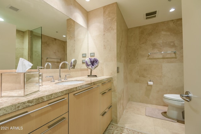 bathroom featuring a tile shower, vanity, tile walls, and toilet