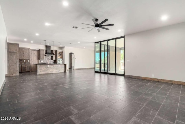 2009 S Raindance Rd, Apache Junction, AZ 85119 - unfurnished living room with a ceiling fan, expansive windows, recessed lighting, and arched walkways