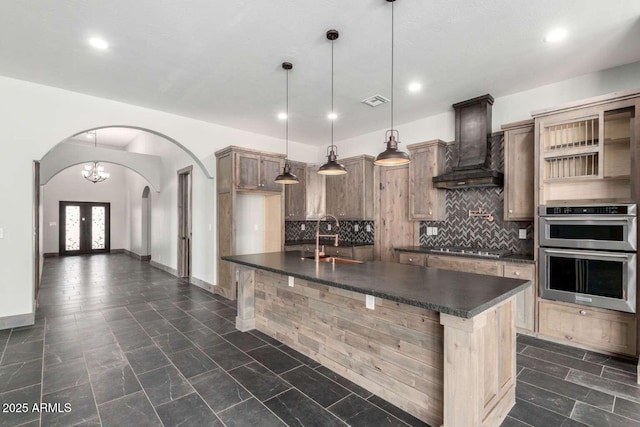 2009 S Raindance Rd, Apache Junction, AZ 85119 - kitchen with dark countertops, custom range hood, arched walkways, double oven, and recessed lighting