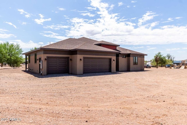 2009 S Raindance Rd, Apache Junction, AZ 85119 - view of front of house with dirt driveway, an attached garage, stucco siding, and roof with shingles