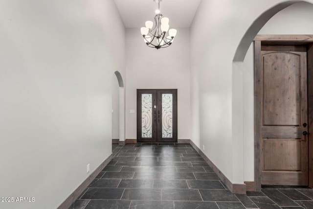 2009 S Raindance Rd, Apache Junction, AZ 85119 - foyer with arched walkways, a chandelier, a high ceiling, french doors, and dark stone finish flooring